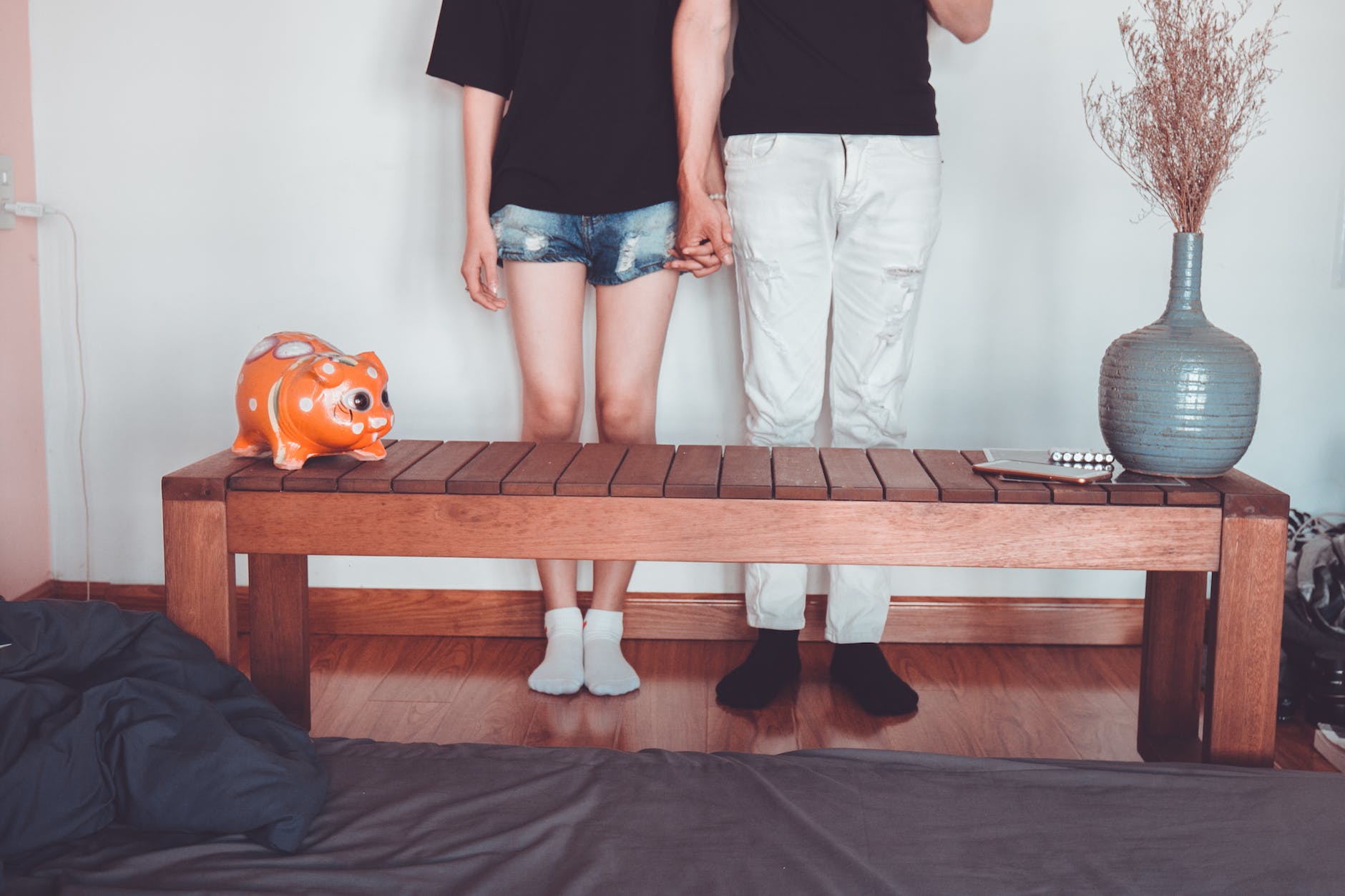 woman and man holding hand standing near brown coffee table inside room